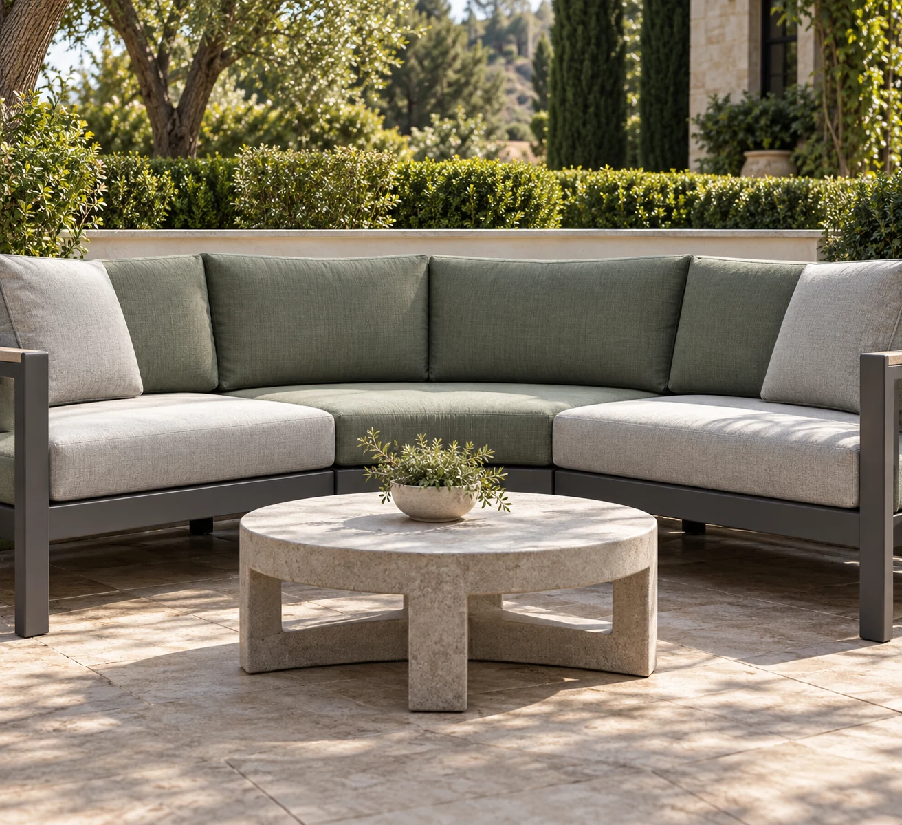 Curved modular outdoor sectional with green and beige cushions around a round table