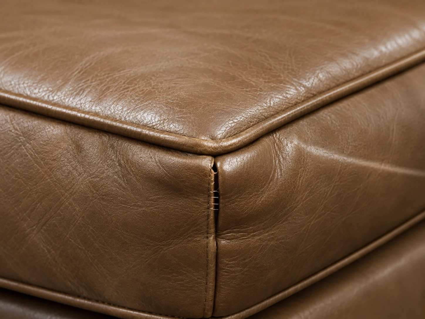 Piping and welt detail on a brown leather cushion corner
