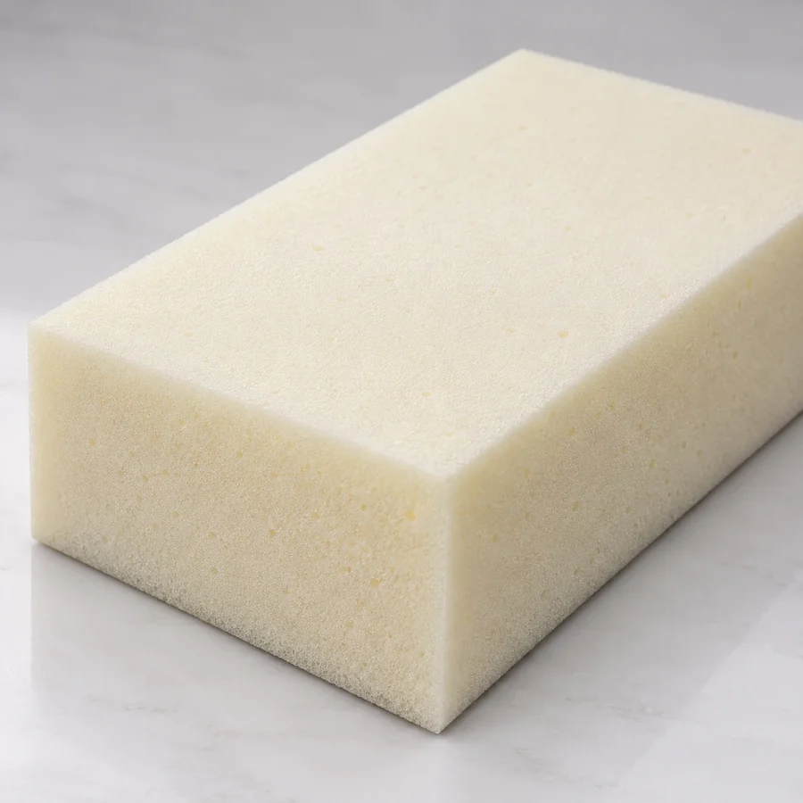 Block of cream high-resilience upholstery foam on a pale bench