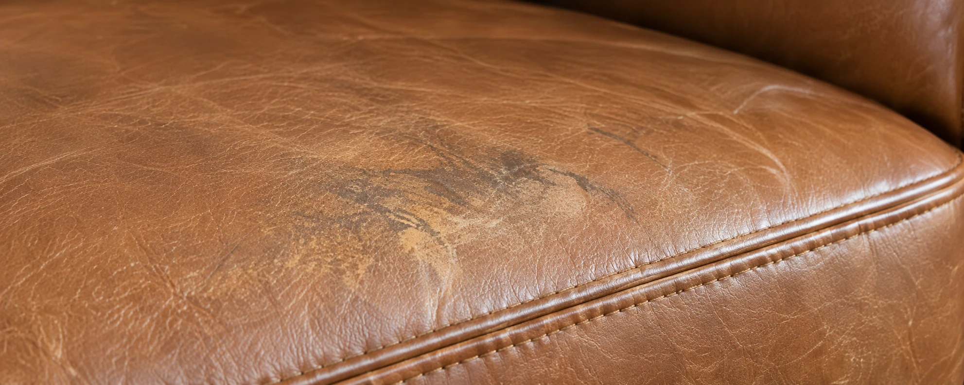 A tan leather seat with the color worn away in a pale patch