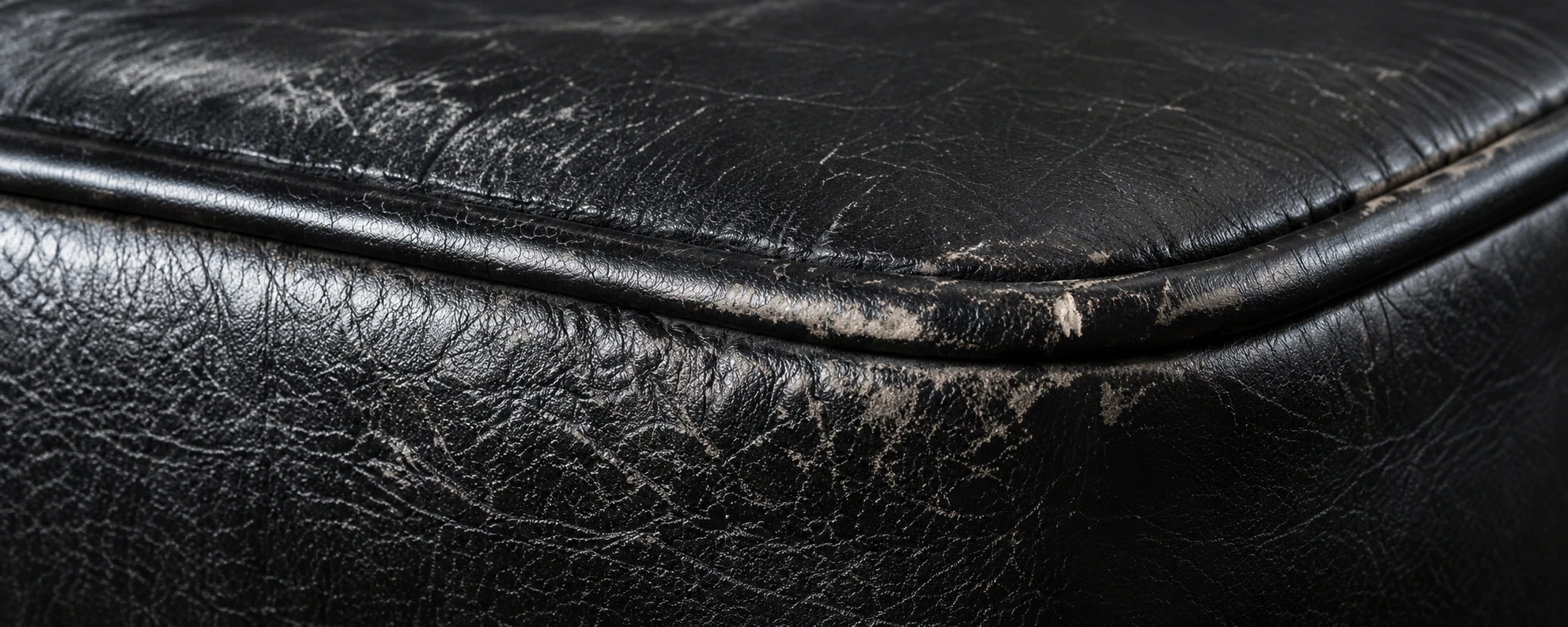 Worn piping along the edge of a black leather cushion