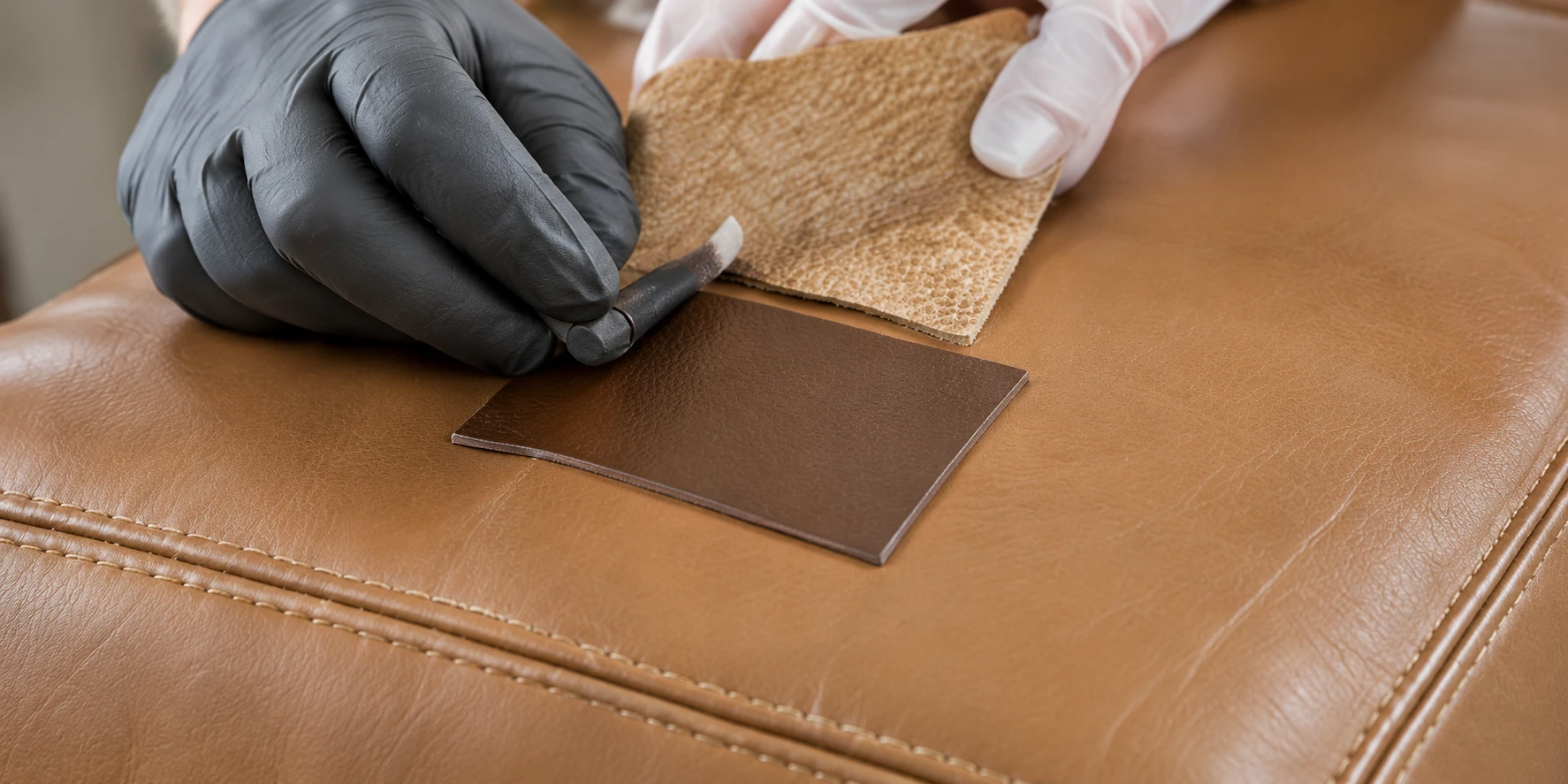 A leather sample held against a tan panel to check color and texture