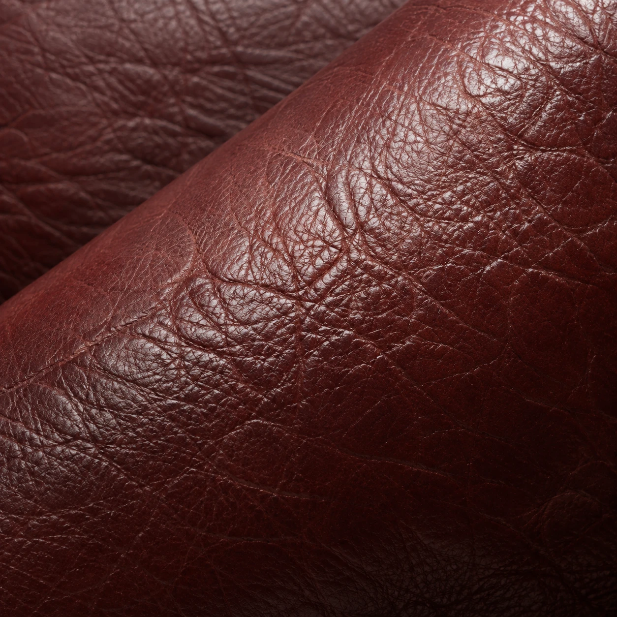 Deep red leather with its color worn thin across the grain