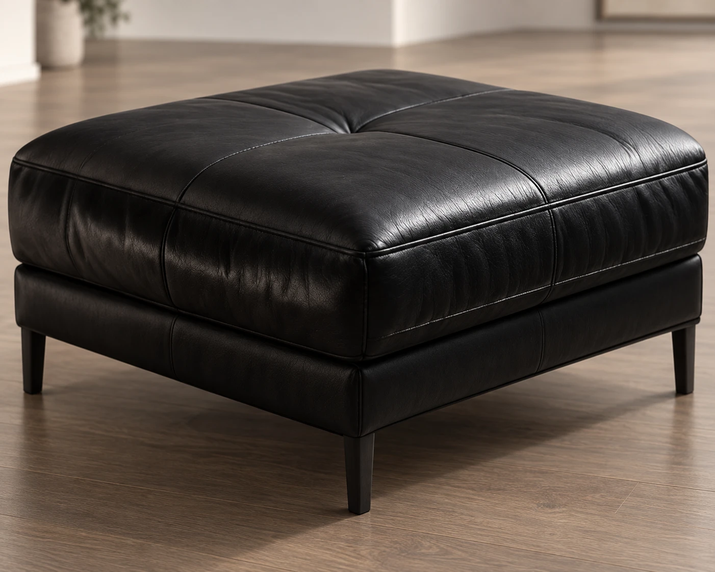 A black leather ottoman on slim tapered legs