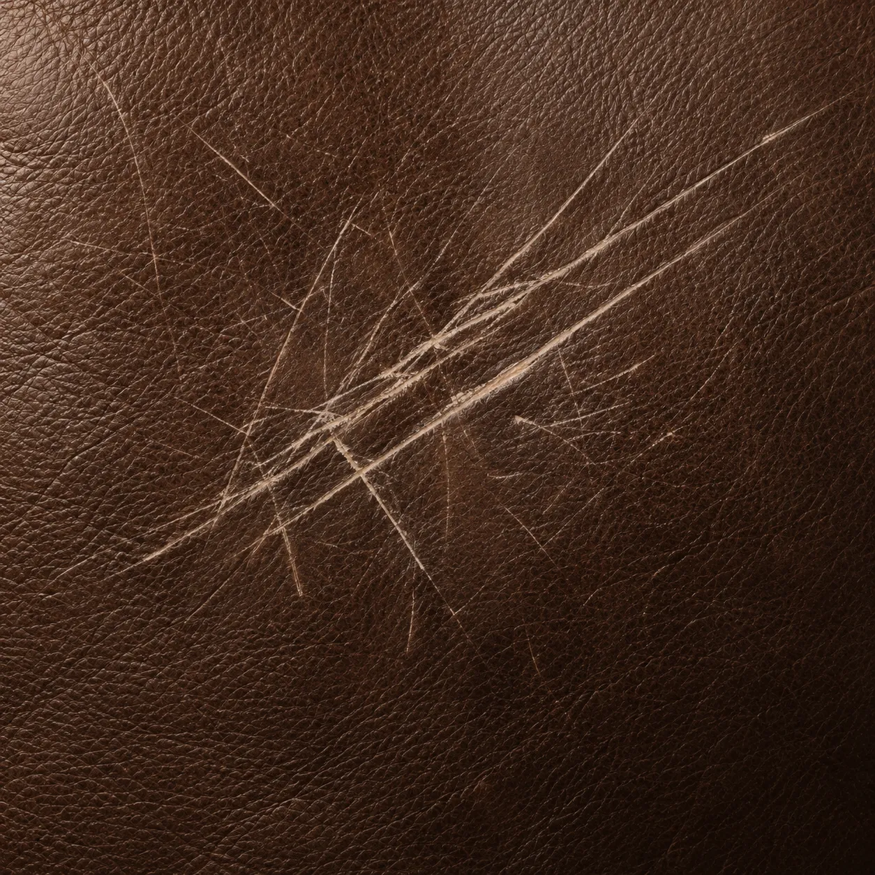 Fine scratches cut across brown leather upholstery