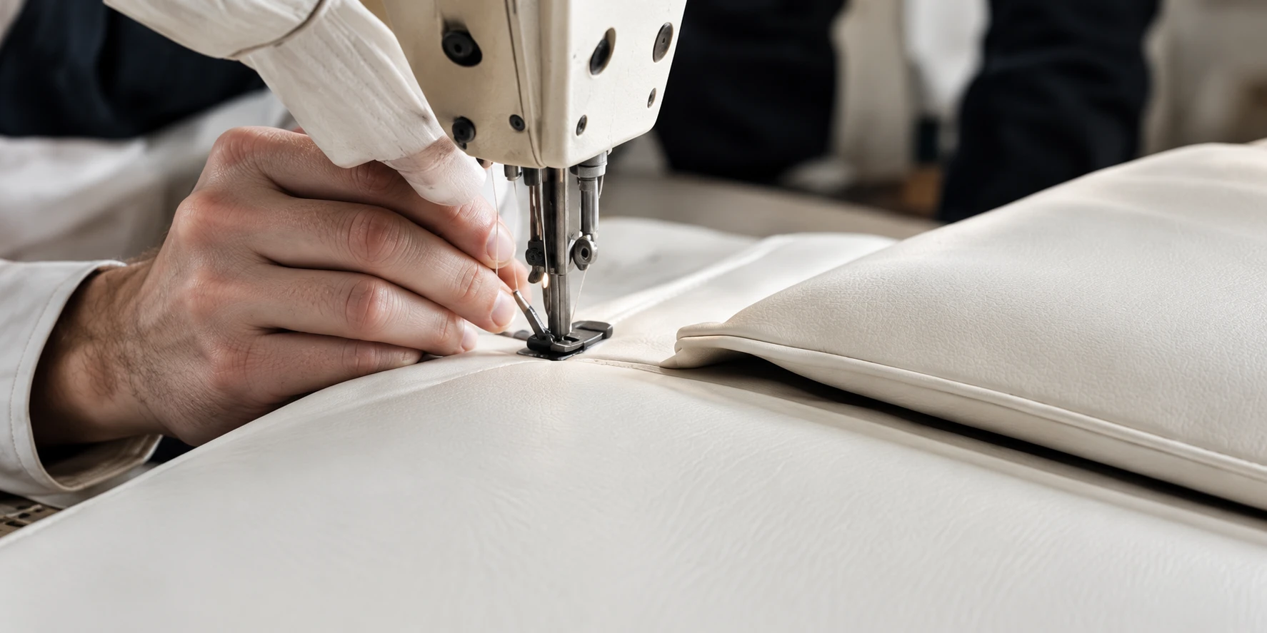 A cream leather panel being sewn on an industrial machine
