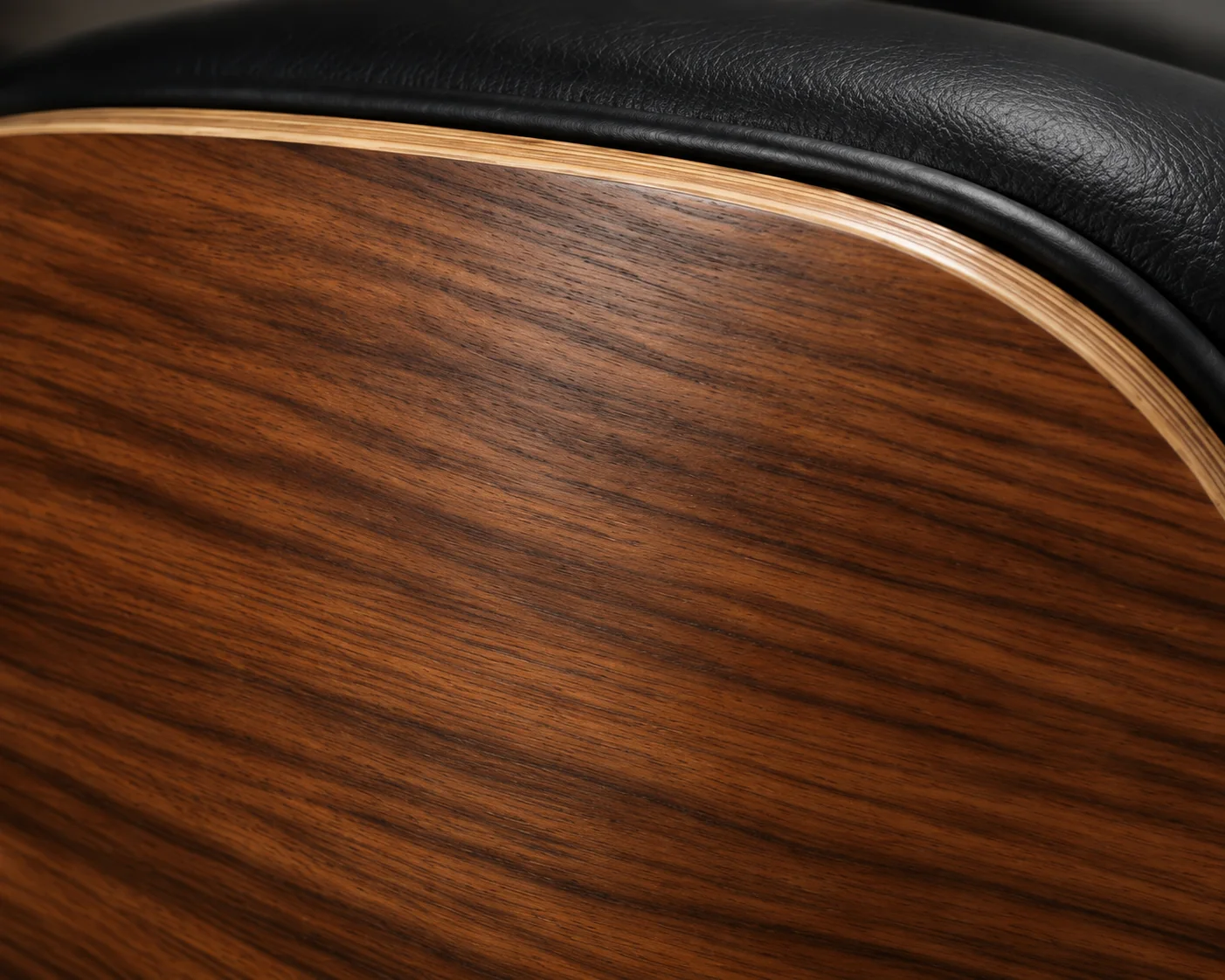 Walnut veneer meeting black leather on an Eames lounge chair