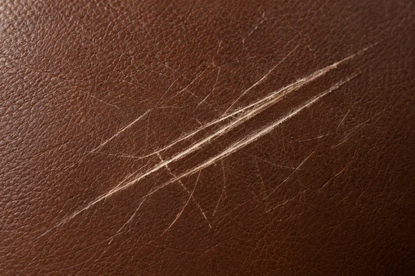 Scratches across a brown leather sofa panel