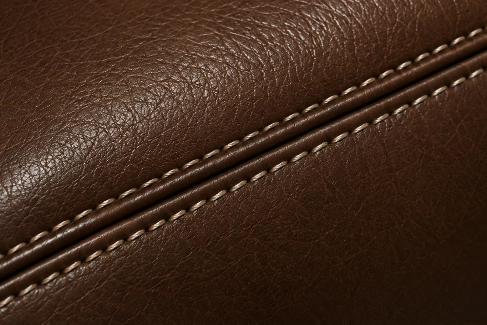 Double-stitched seam on a brown leather sofa