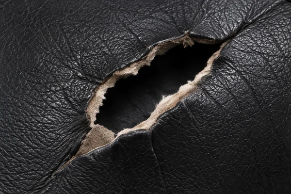 A tear opening in a dark leather panel