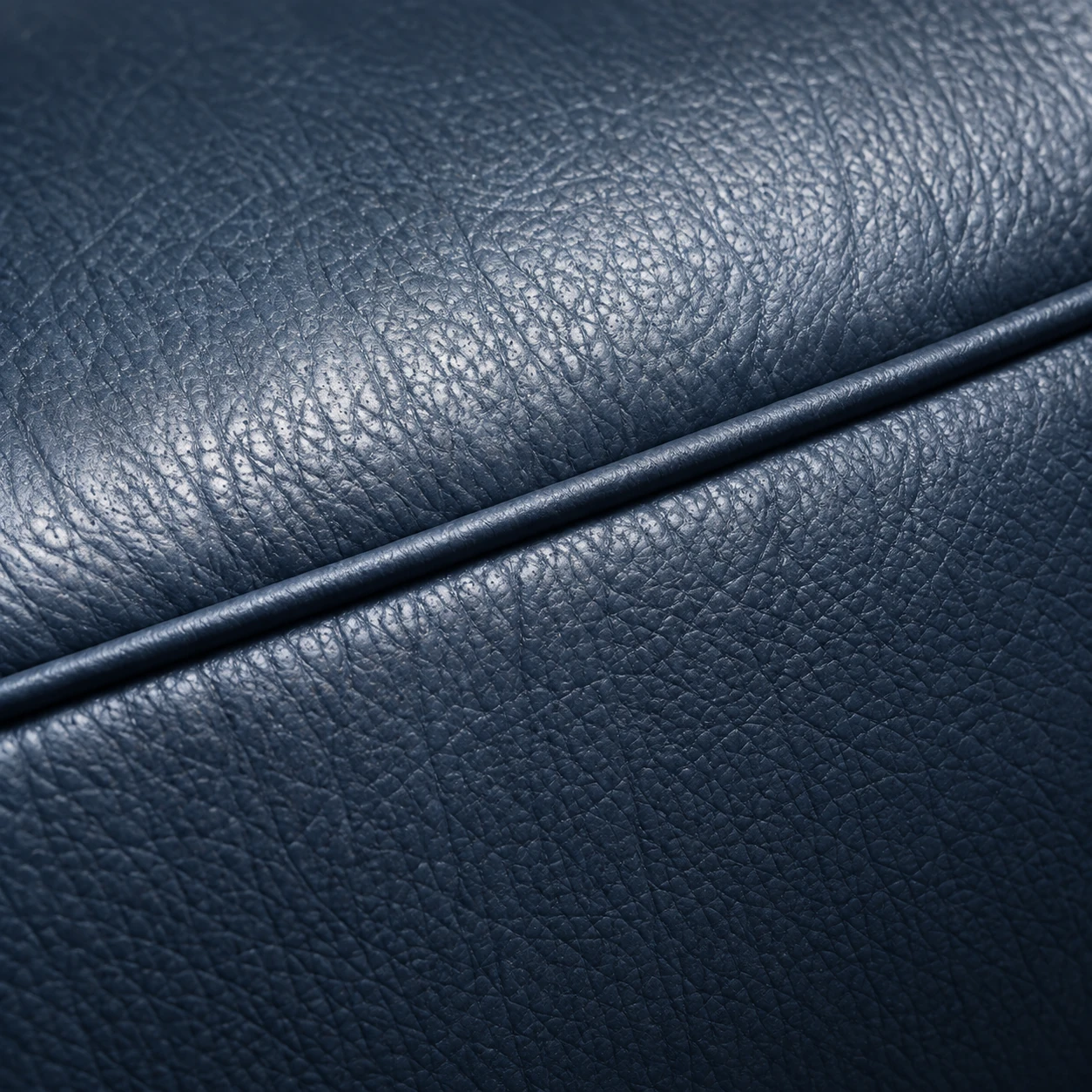 A navy leather sofa with the upper panel sun-faded paler than the panel below