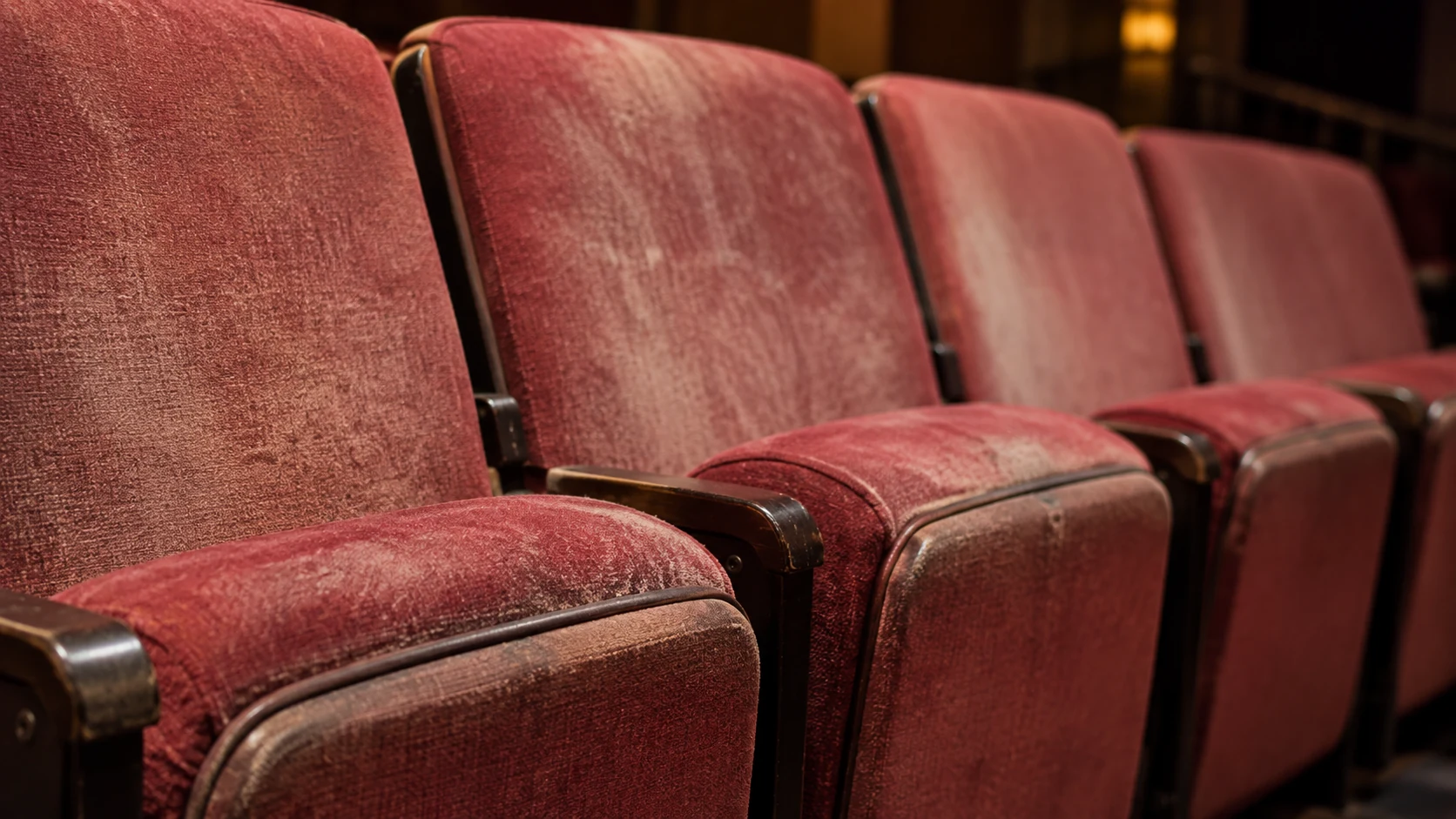 Row of faded red velvet theater seat covers