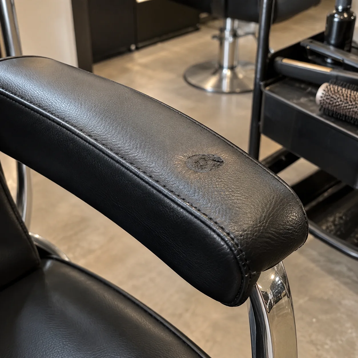 A flat iron burn on a salon chair armrest