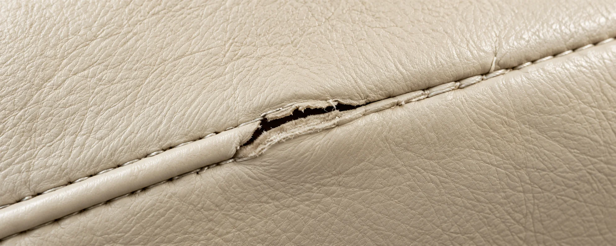 A split seam on a cream leather Herman Miller cushion