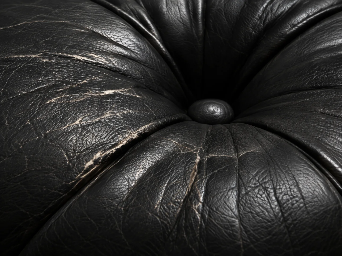 Wear around a tufted button on black Herman Miller leather