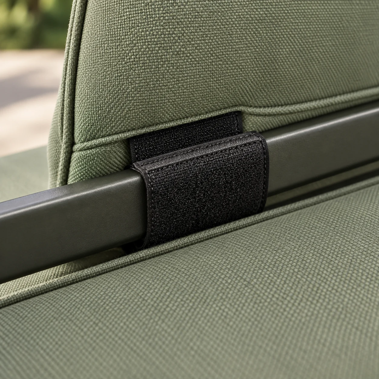 Hidden dark strap fastening an outdoor cushion to the rail of its frame