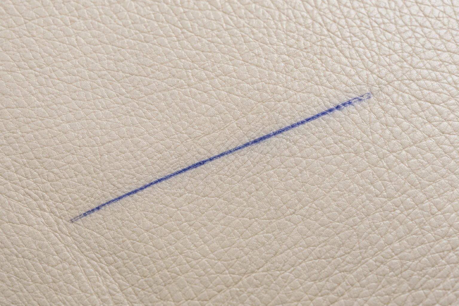 A single thin blue ballpoint line drawn across a cream leather seat panel