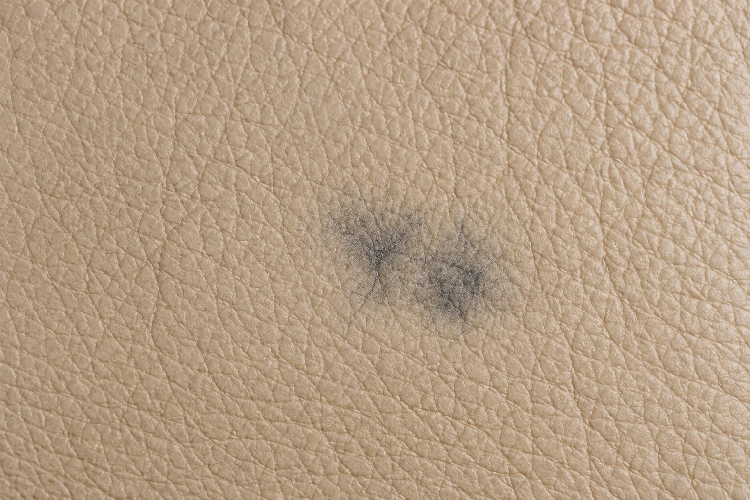 An old grey ink stain faded into the grain of cream leather