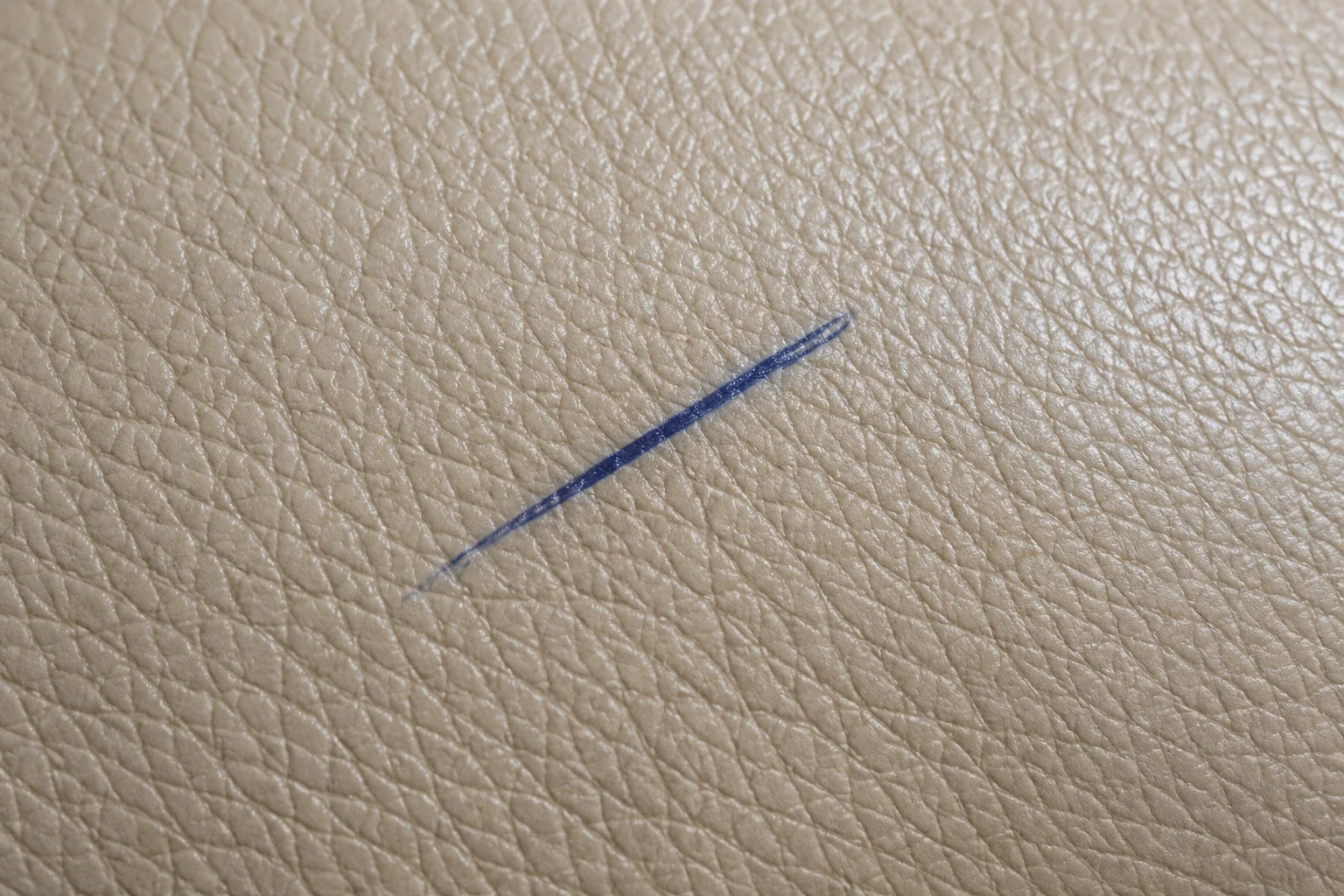 A blue ballpoint line drawn across a panel of beige leather