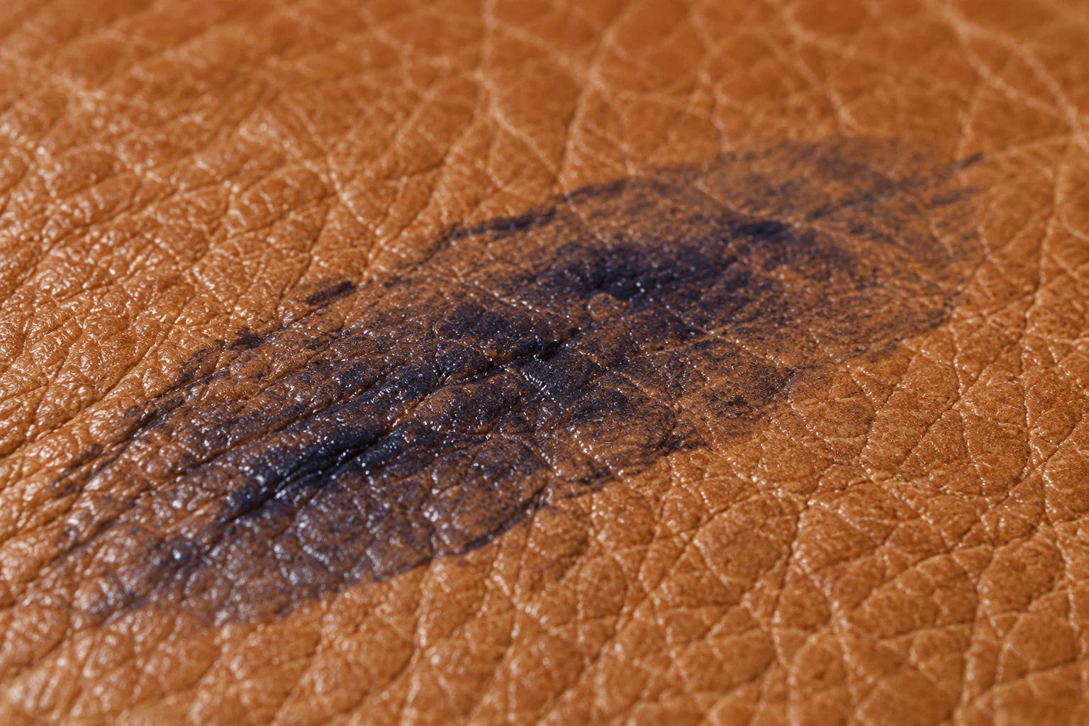 The stroke now a broad dark smear spread well beyond where the pen touched the tan leather
