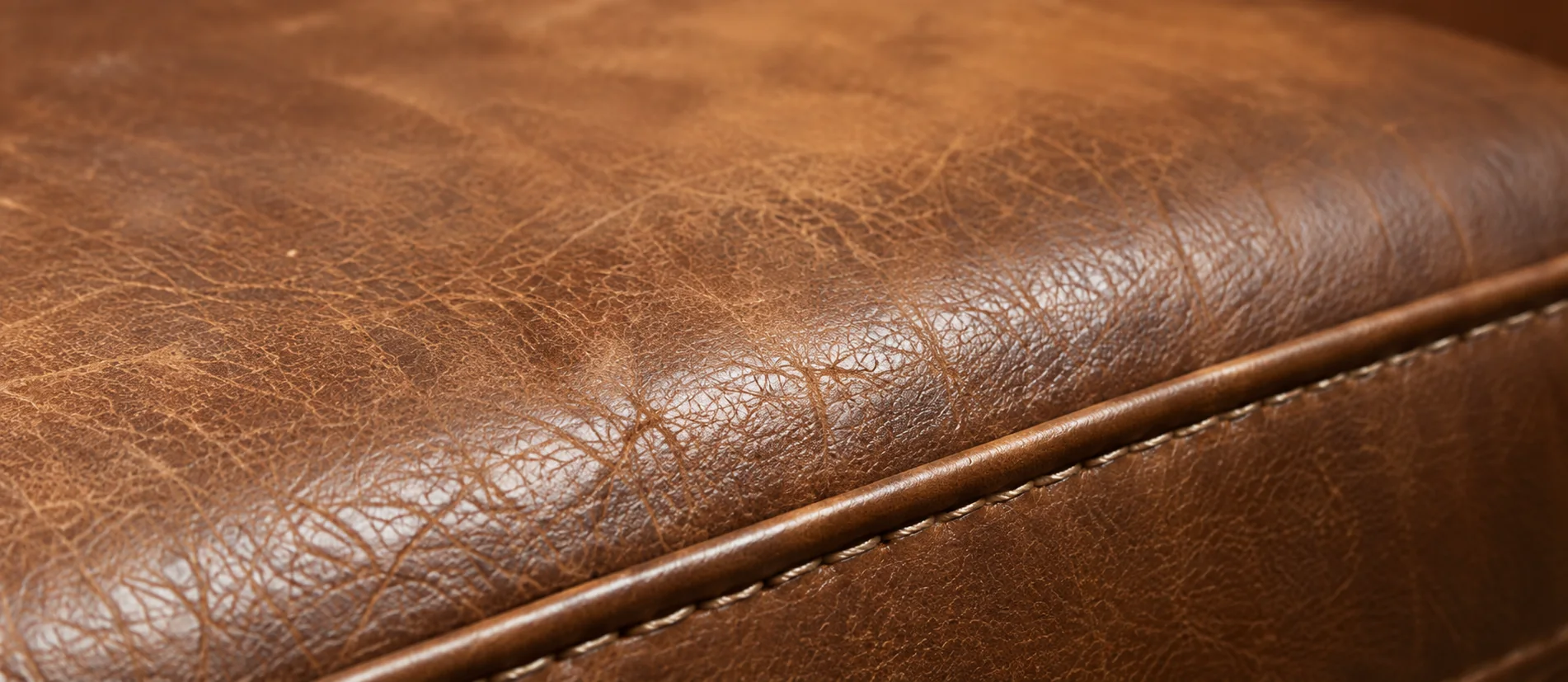 Brown leather cushion with the color worn thin across the seating area