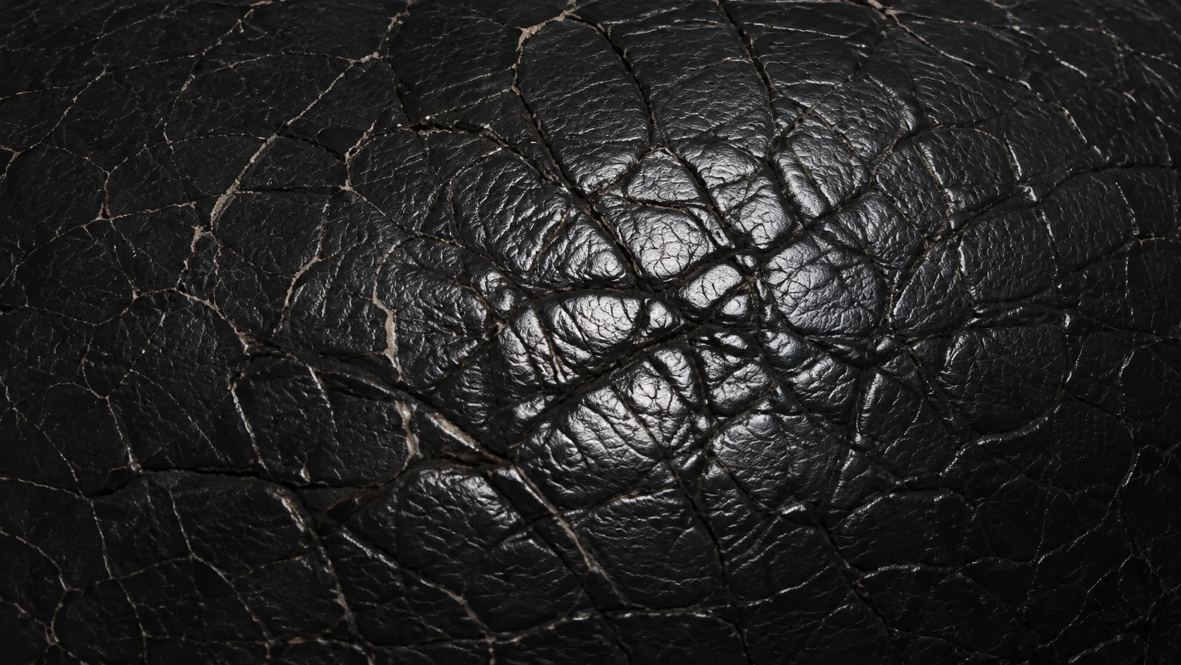 Network of fine cracks across a dried brown leather seat panel