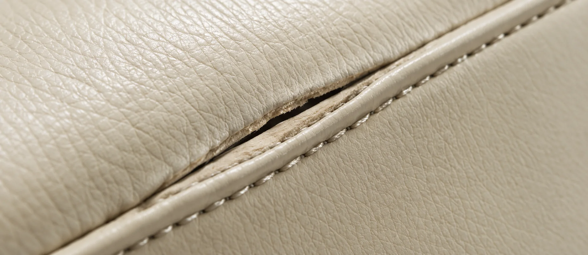 Split stitching along a welted seam on a cream leather cushion