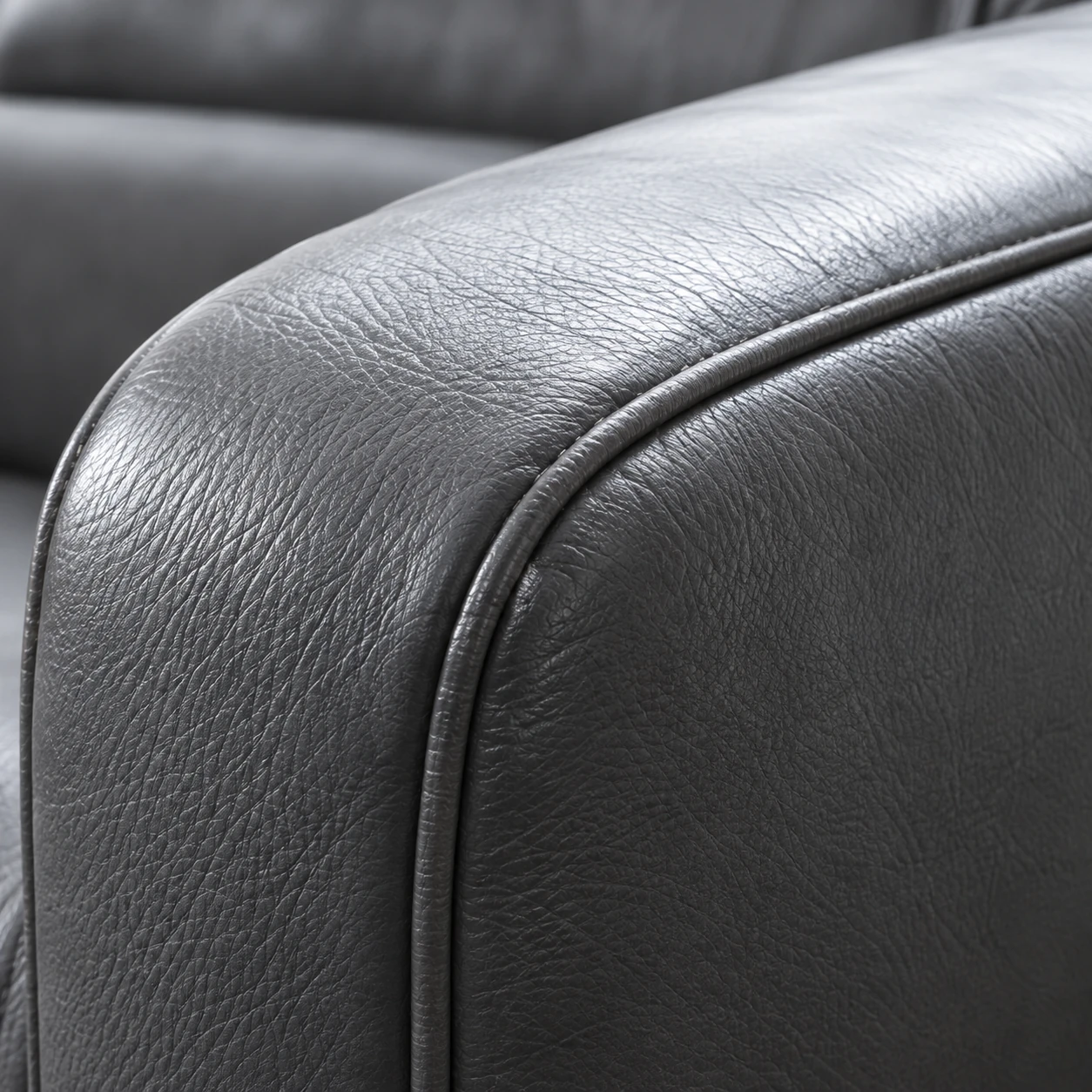 Leather upholstery repair: a grey sofa armrest crown worn smooth