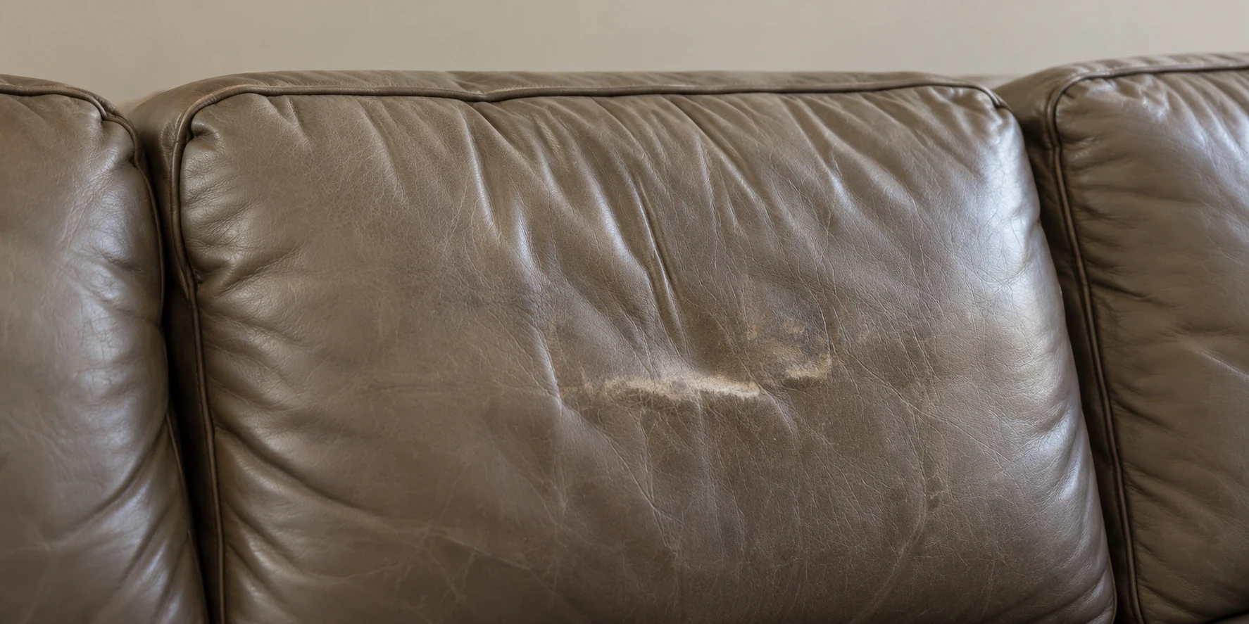 An olive leather backrest panel scuffed pale in the middle where heads and hands rest