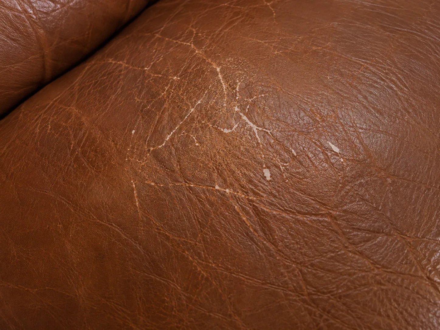A leather seat with color worn away across the contact area