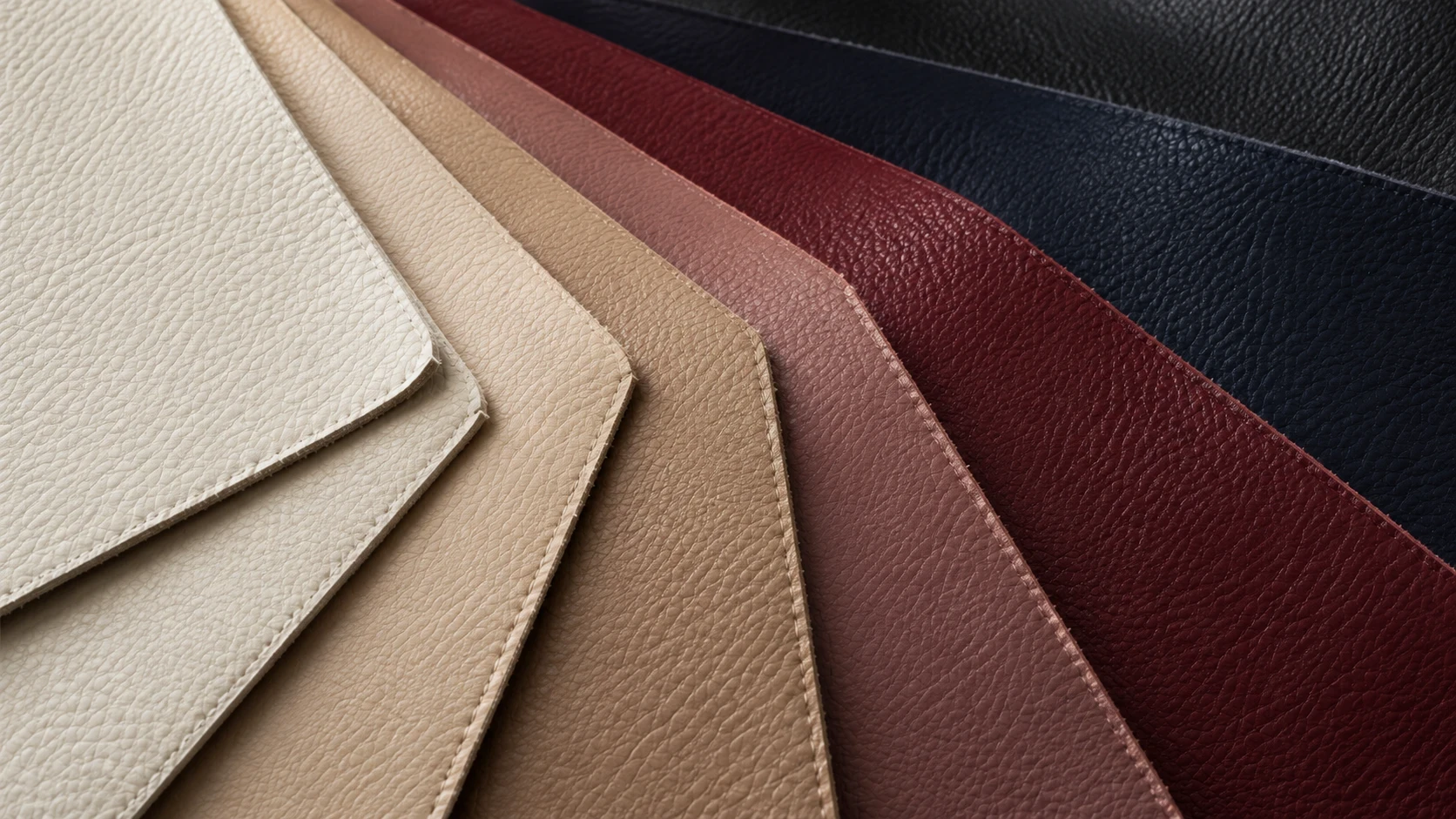 A gloved hand holding a tan leather swatch over a colour matching bench
