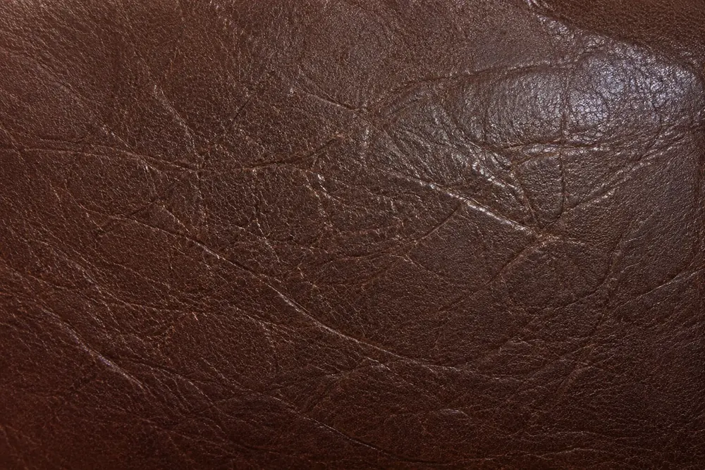 Close-up of dark brown leather showing the faded, uneven colour a repair has to be mixed against