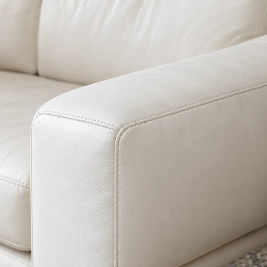 Rolled arm of a cream leather sofa seen from the front corner