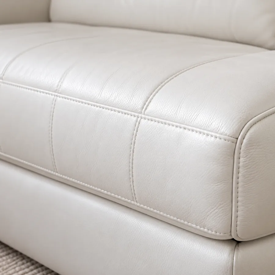 Front edge of a cream leather seat cushion above the sofa base