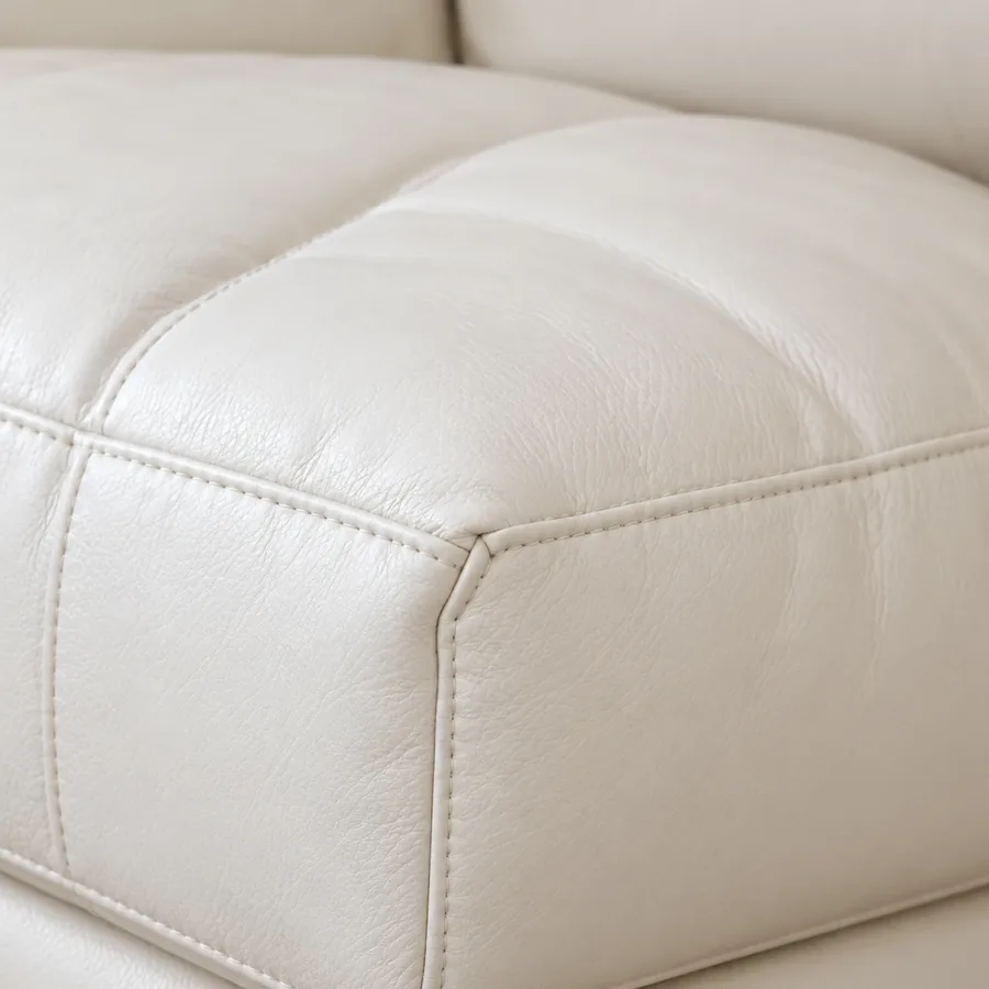 Corner of a cream leather seat cushion with a stitched top seam