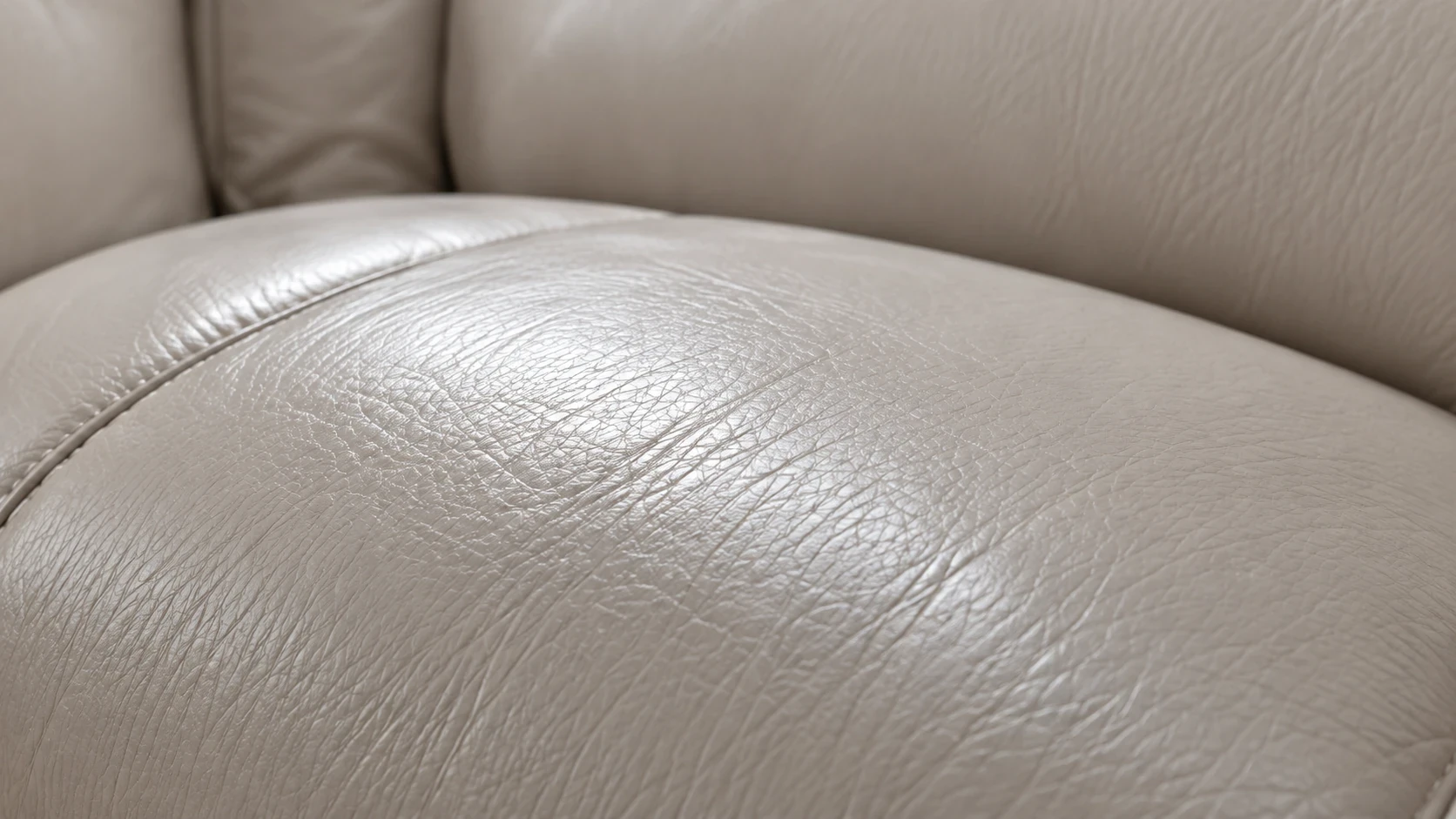 A hand working conditioner into a brown leather cushion