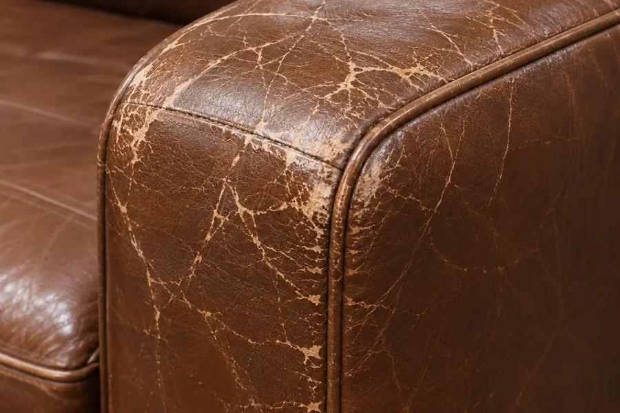 Cracked and flaking finish over the crown of a leather armrest