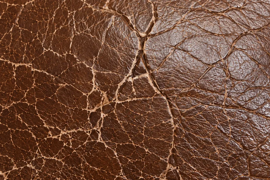 Leather crack repair — fine surface cracks forming a tight web across a brown leather panel
