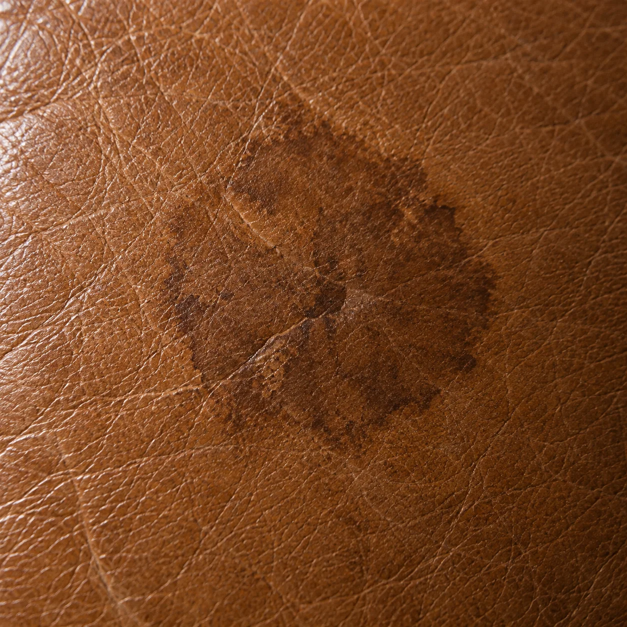 Small burn mark scorched into a brown leather cushion