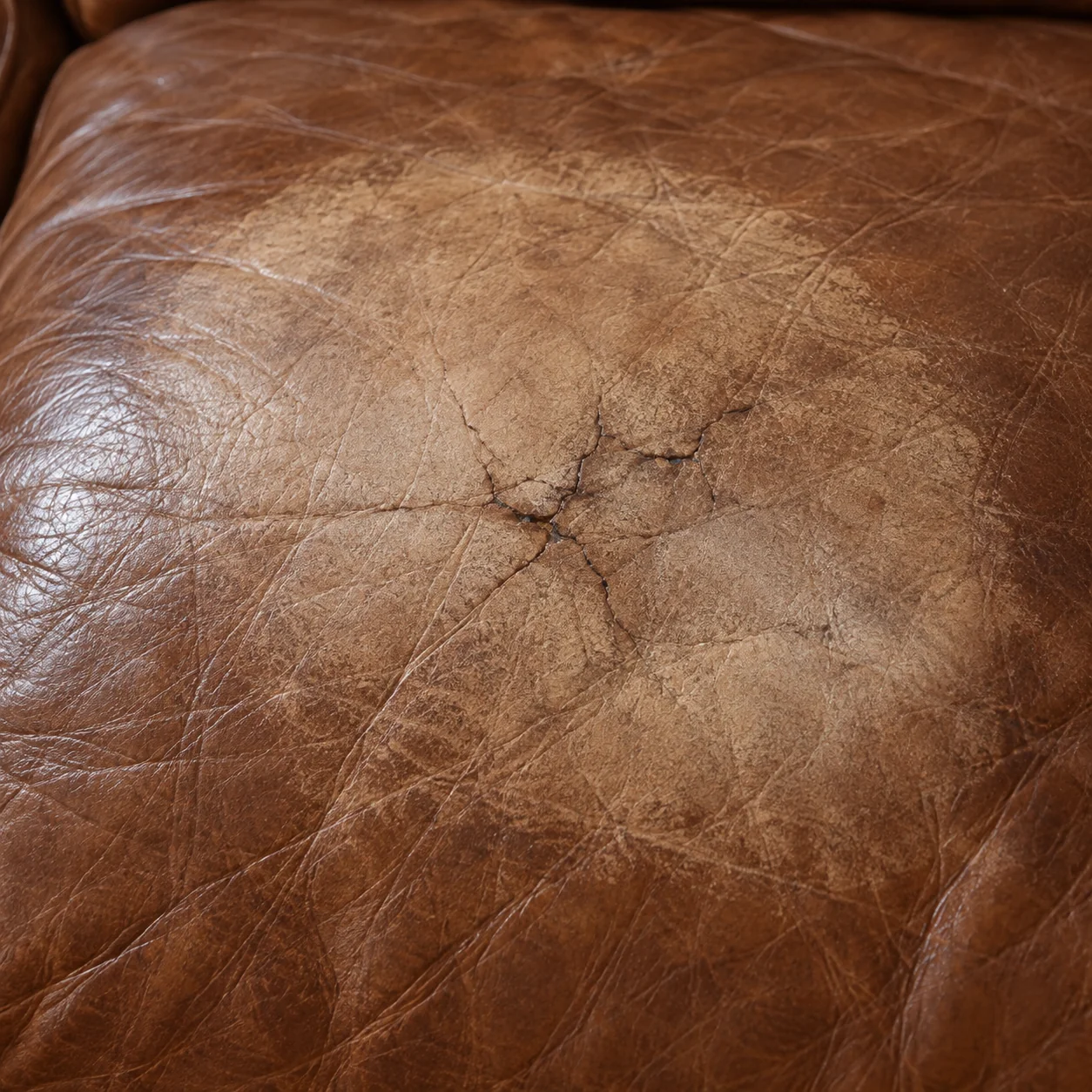 Faded patch where colour has worn off a brown leather cushion