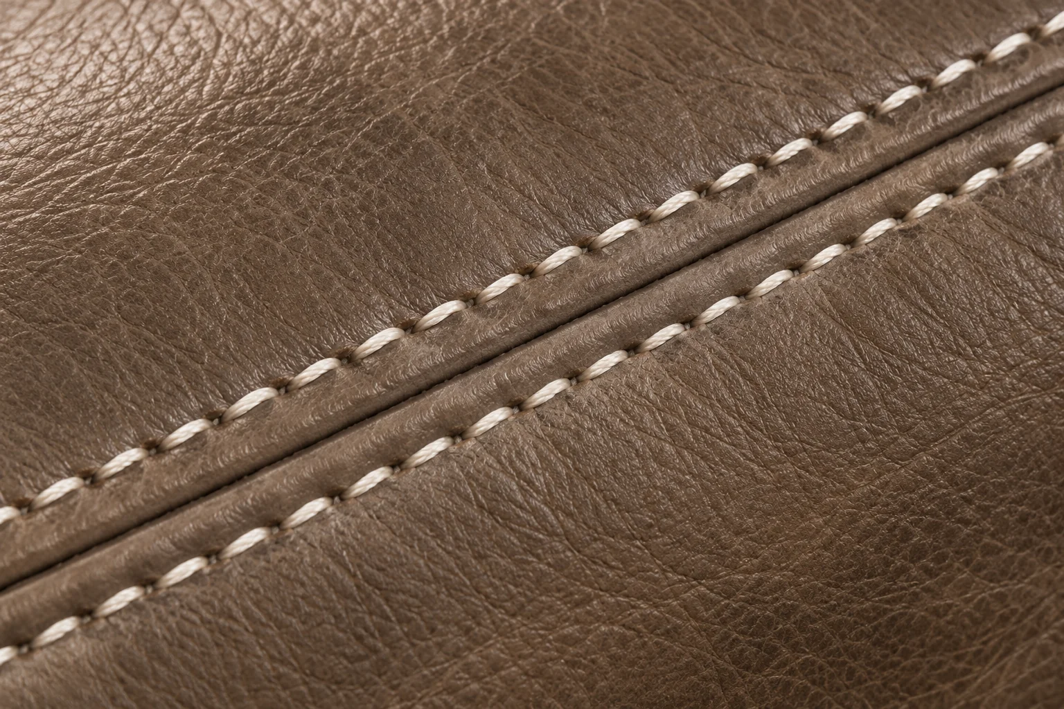 Cream contrast stitching running along a taupe leather cushion seam