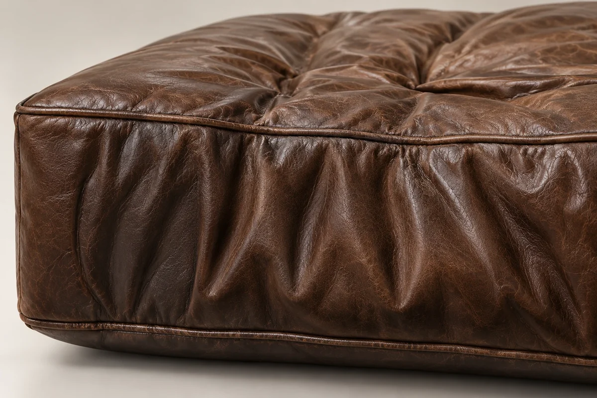 Brown leather cushion cover creased and worn over a core that still holds its shape