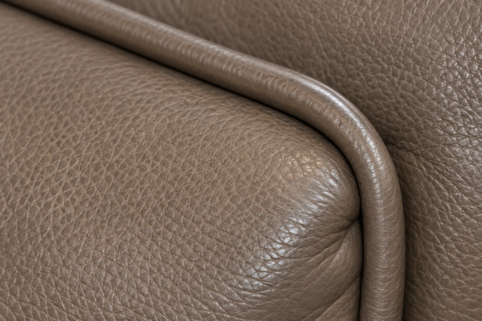 Rolled leather piping along the edge of a taupe cushion
