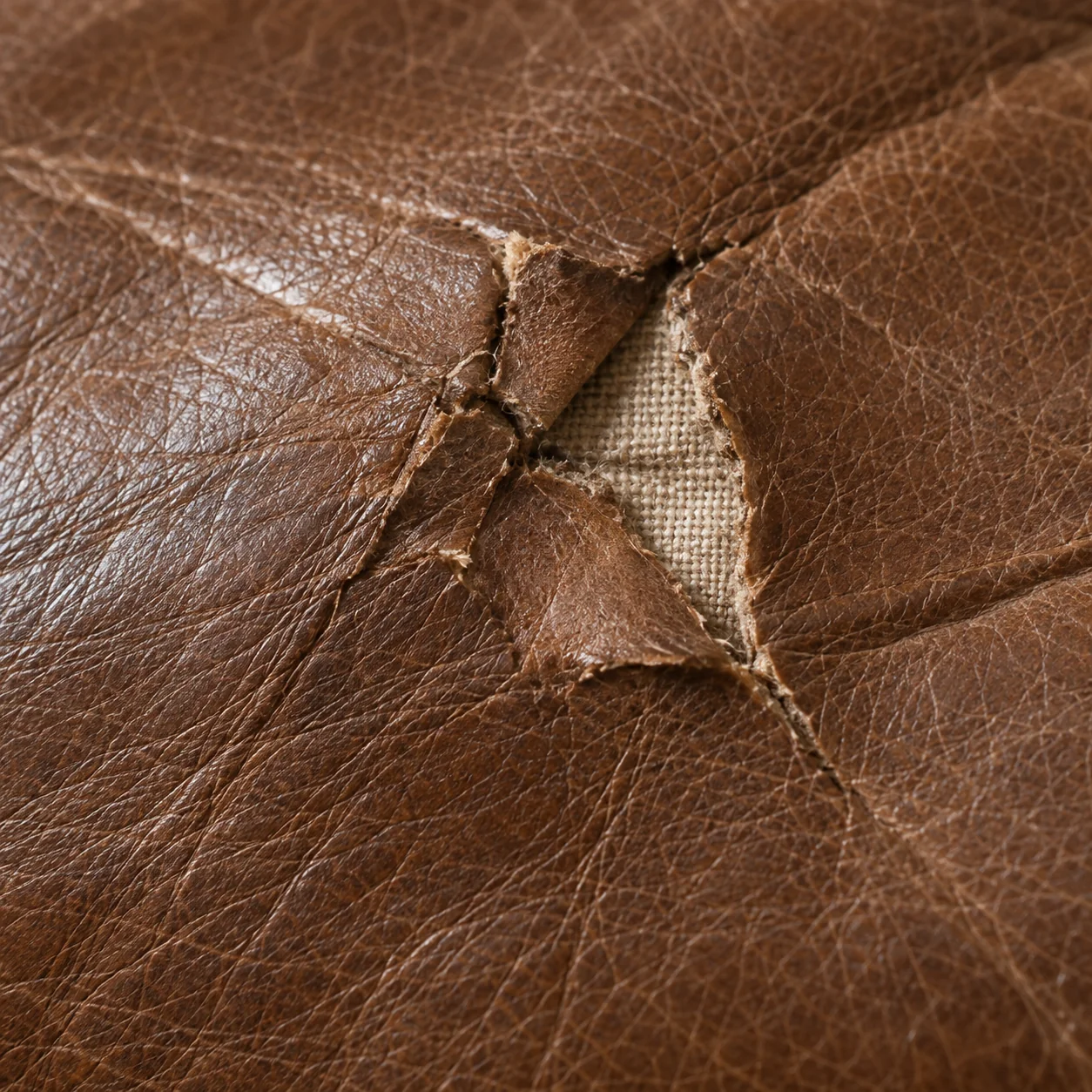 Small tear opening in a brown leather cushion cover