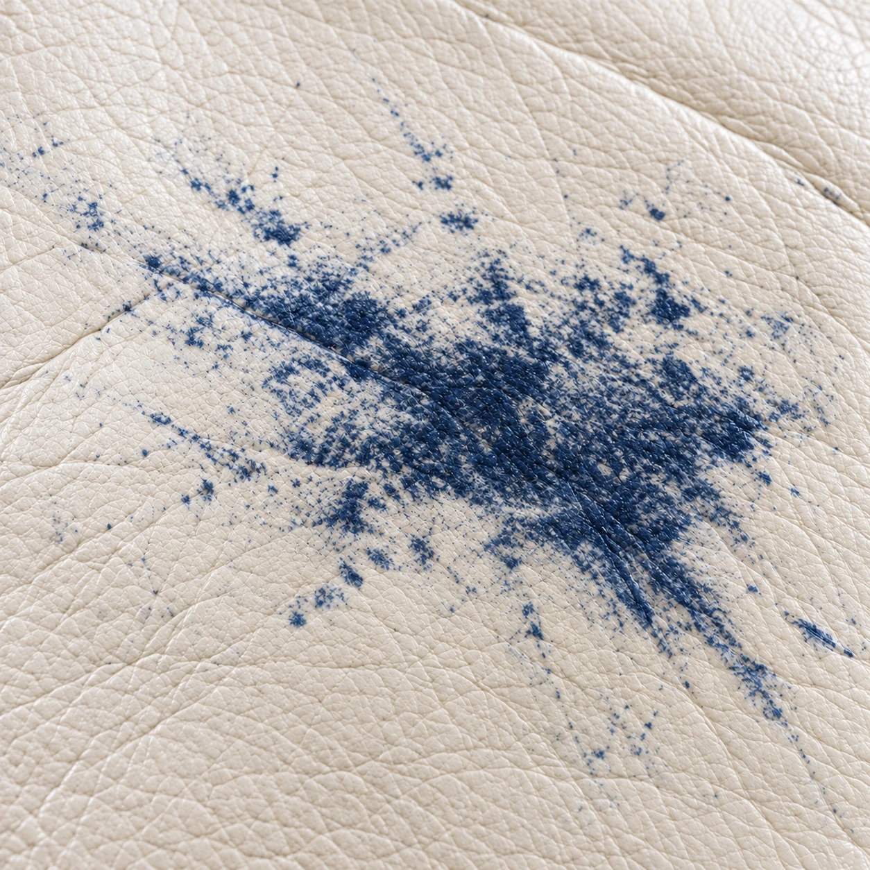 A blue dye transfer burst across cream leather