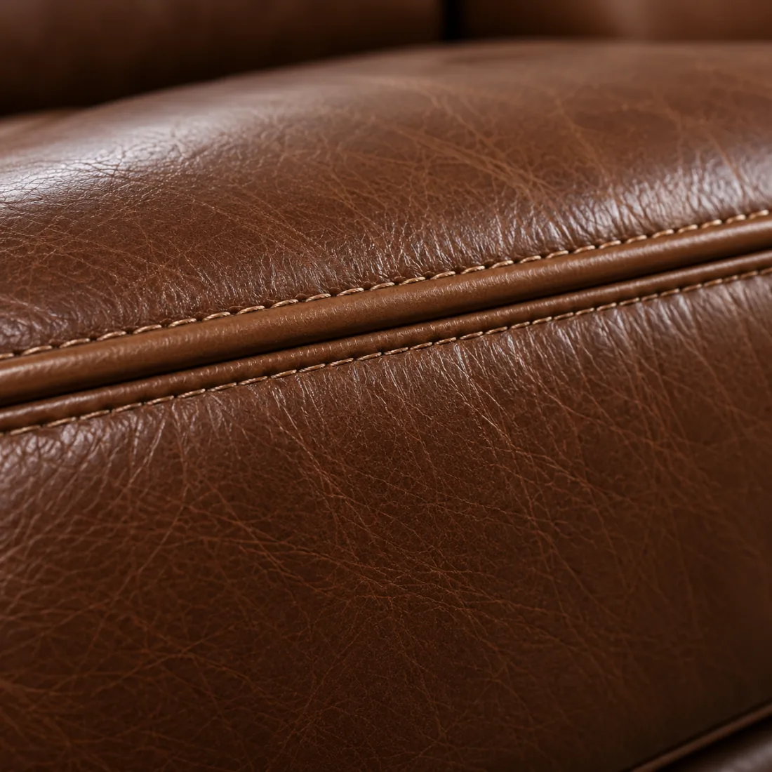 Close view of a stitched welt running along the edge of a brown leather cushion