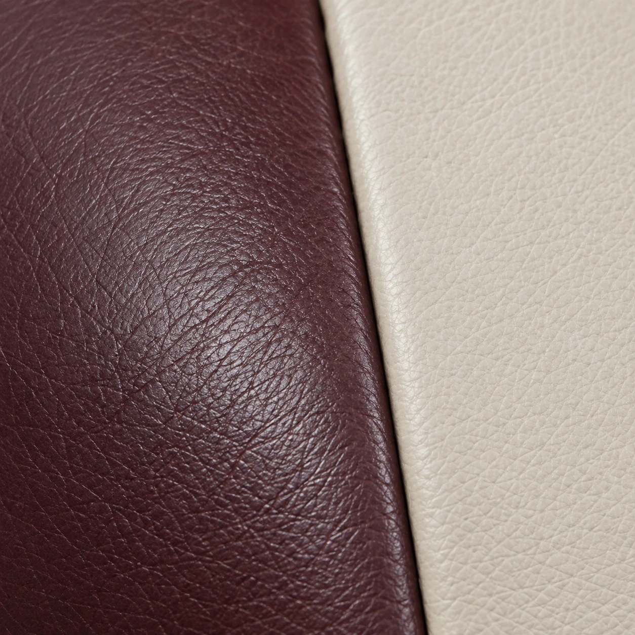 A burgundy leather panel meeting a cream panel on one sofa