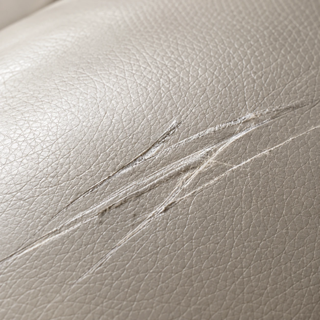 Fine scratch lines across a cream leather panel