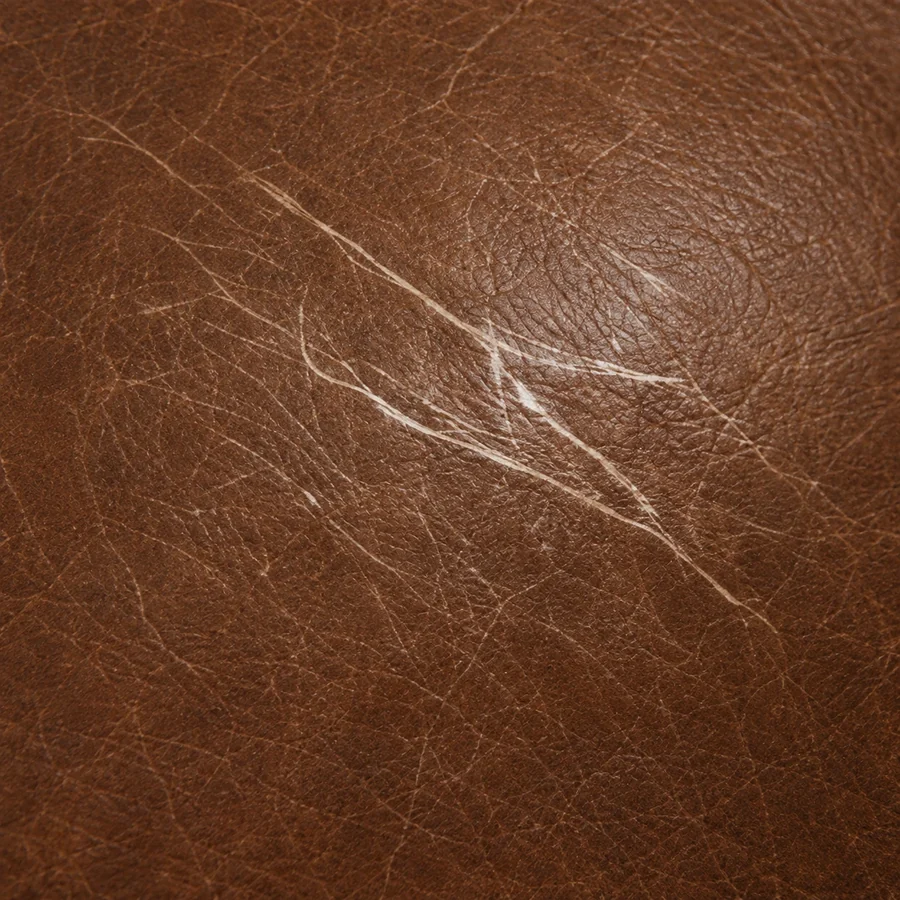 Close-up of fine scratches cut into a brown leather surface