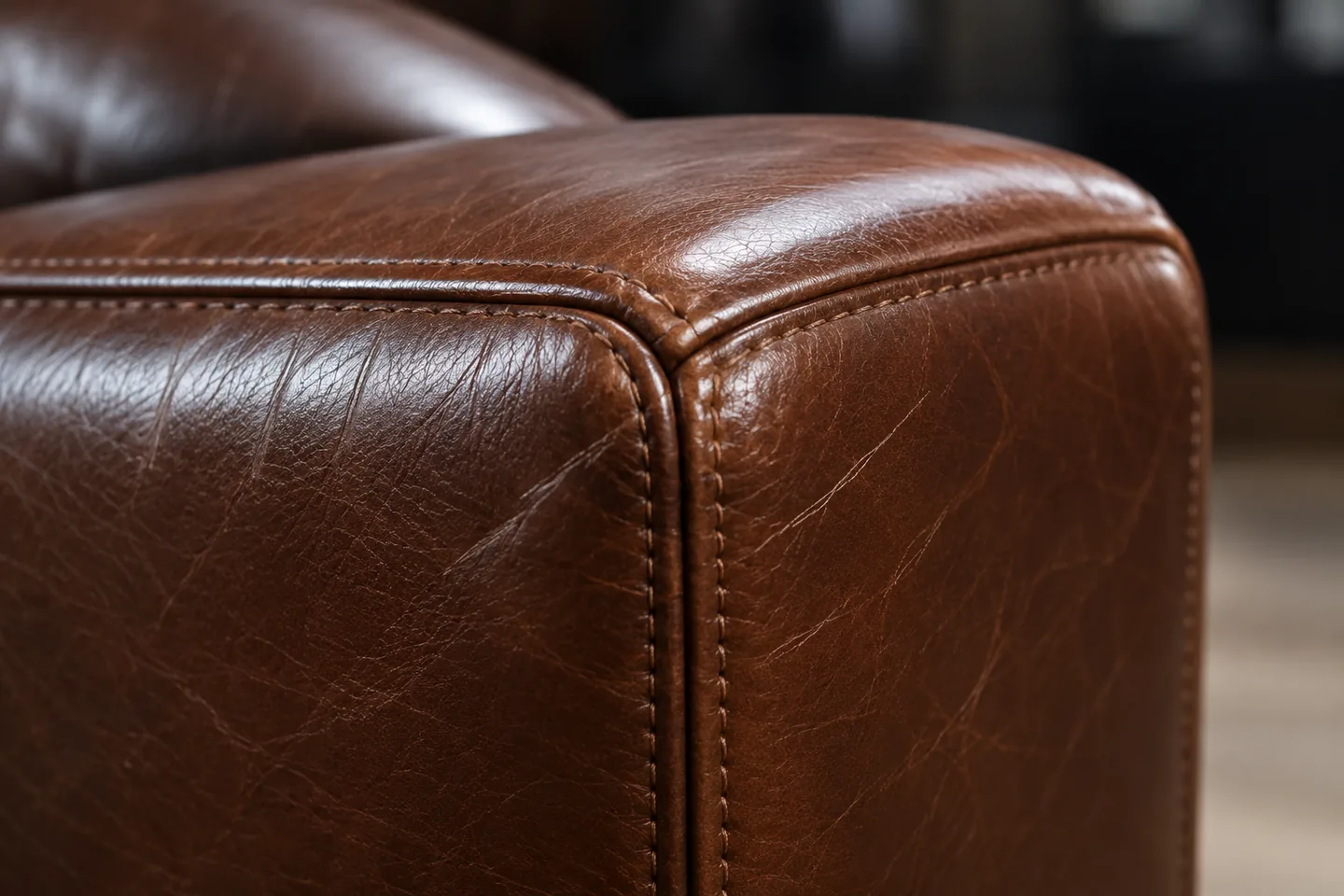 The back corner of a brown leather chair rubbed pale along the seam